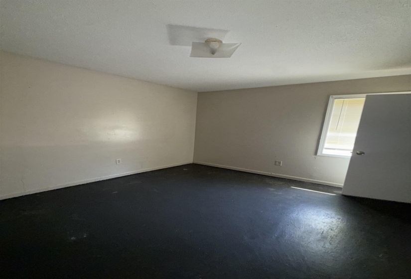 Empty room with finished concrete flooring and baseboards
