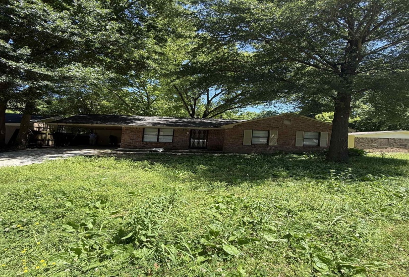 View of front of home featuring a carport, brick siding, and driveway