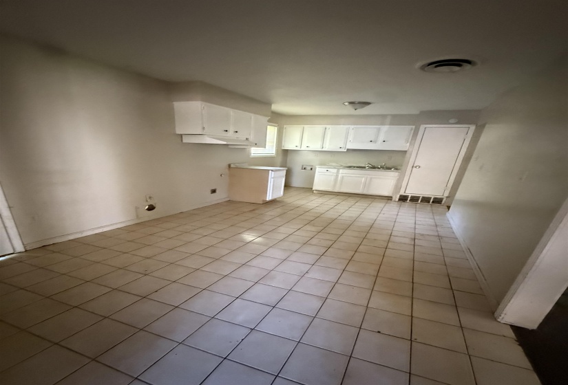 Kitchen featuring light tile patterned flooring, white cabinets, a sink, and baseboards