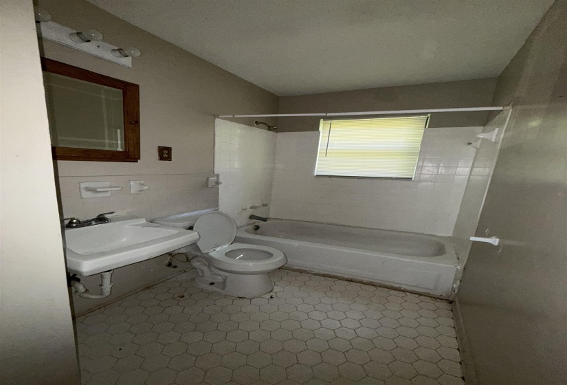 Bathroom with washtub / shower combination, toilet, and a sink