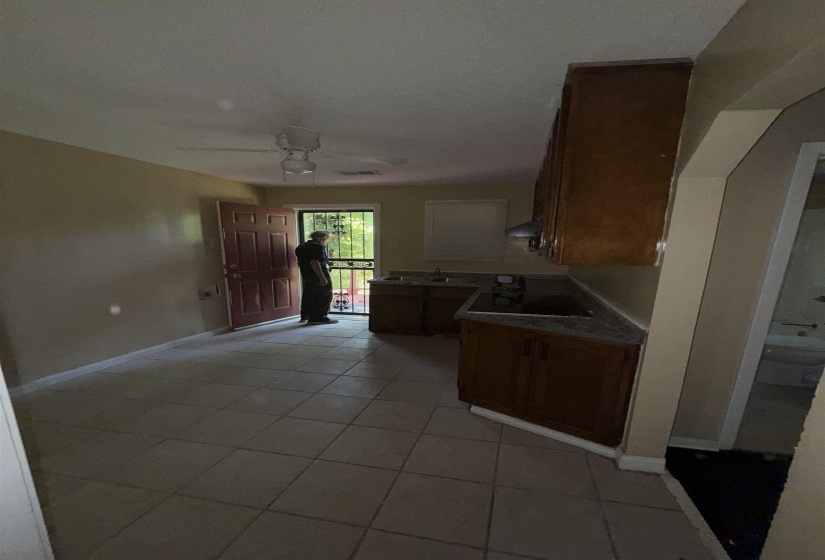 Kitchen with light tile patterned floors, black electric cooktop, a ceiling fan, range hood, and baseboards