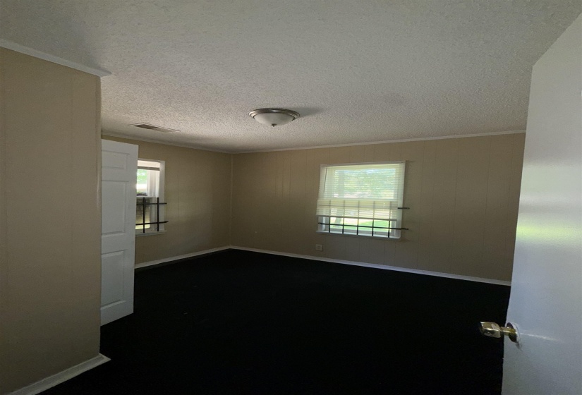 Empty room featuring a textured ceiling, crown molding, and baseboards