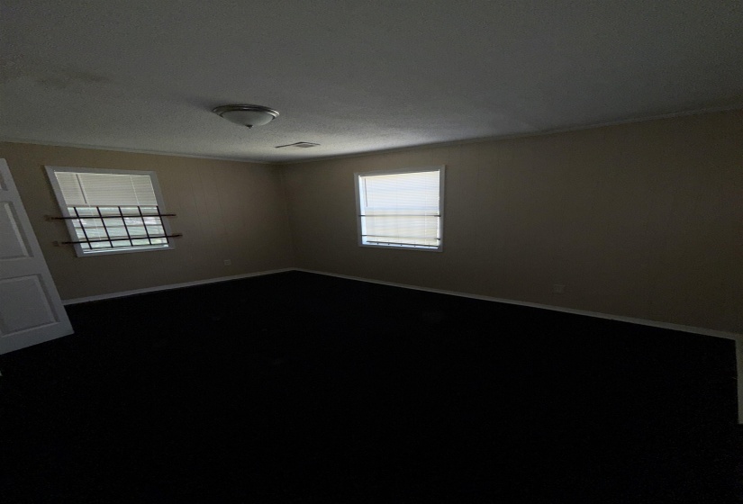 Empty room featuring baseboards, crown molding, and dark carpet