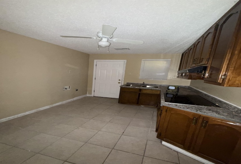 Kitchen featuring black electric stovetop, ceiling fan, light tile patterned floors, under cabinet range hood, and a textured ceiling