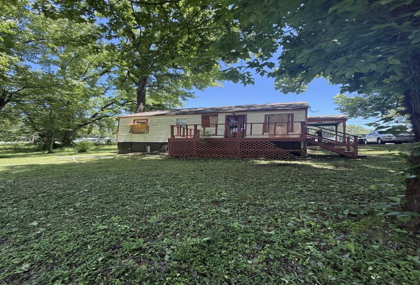 Back of property featuring a wooden deck and a lawn