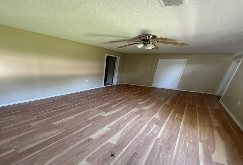 Spare room with wood finished floors, a ceiling fan, a textured ceiling, and baseboards