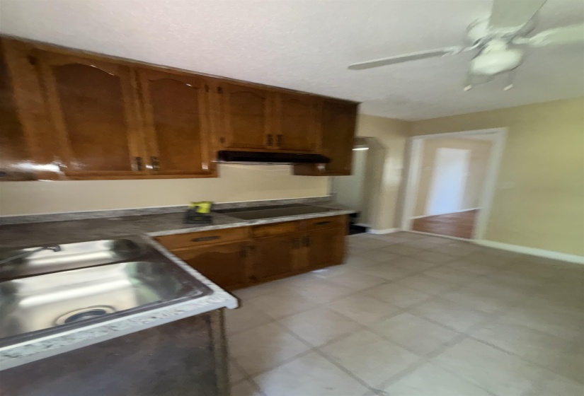 Kitchen featuring under cabinet range hood, brown cabinets, black electric stovetop, and a sink