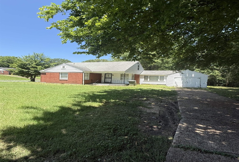 Ranch-style house with a porch, asphalt driveway, a front yard, an attached garage, and an outbuilding