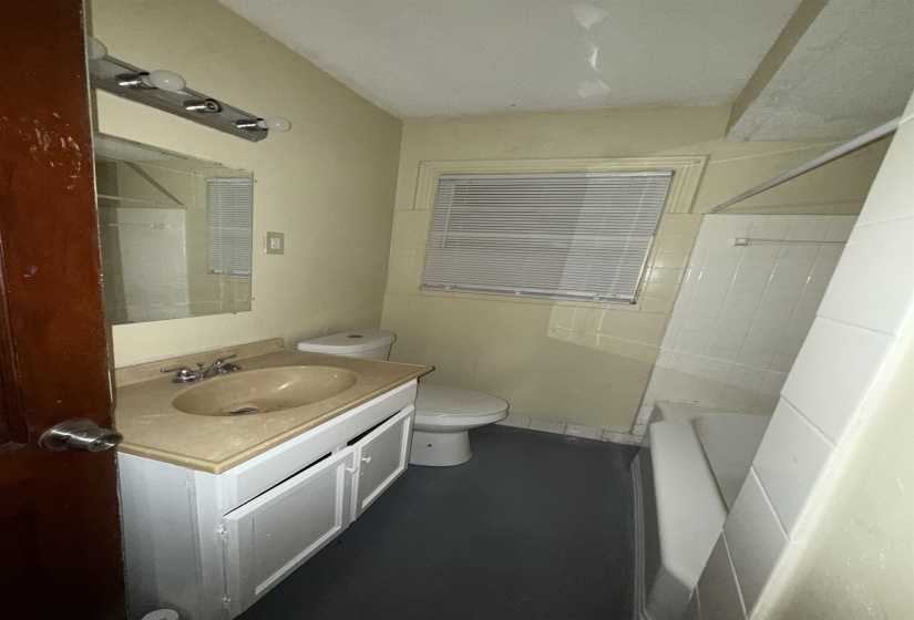 Bathroom with toilet, vanity, and  shower combination