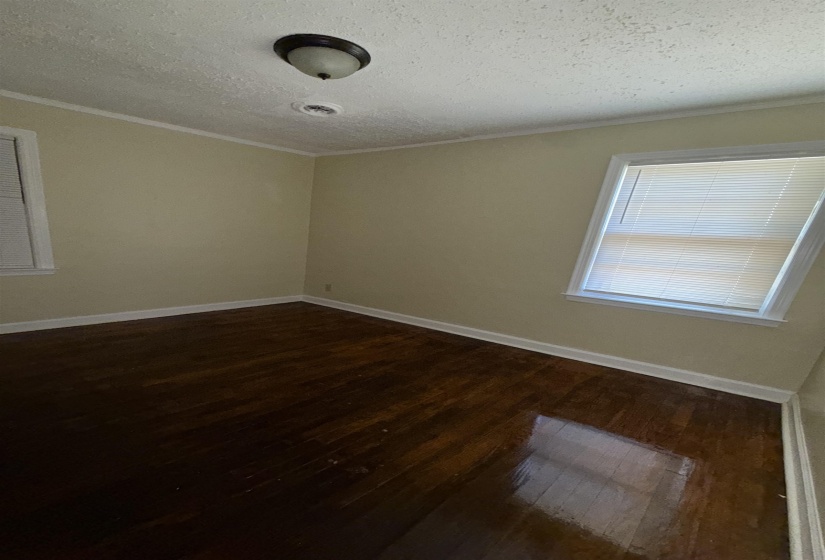 Spare room featuring dark wood finished floors, ornamental molding, a textured ceiling, and baseboards