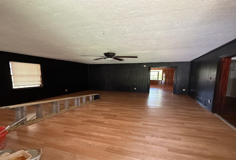Empty room featuring light wood-type flooring, a textured ceiling, and a ceiling fan