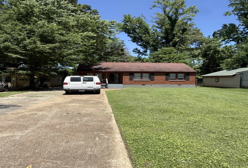View of front facade featuring concrete driveway, a front lawn, and brick siding