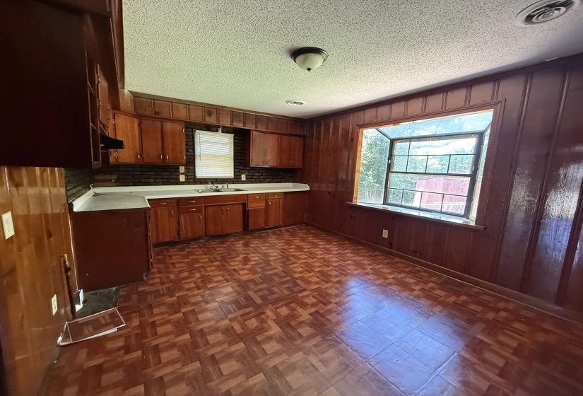 Kitchen with light countertops, a sink, brown cabinetry, a textured ceiling, and under cabinet range hood