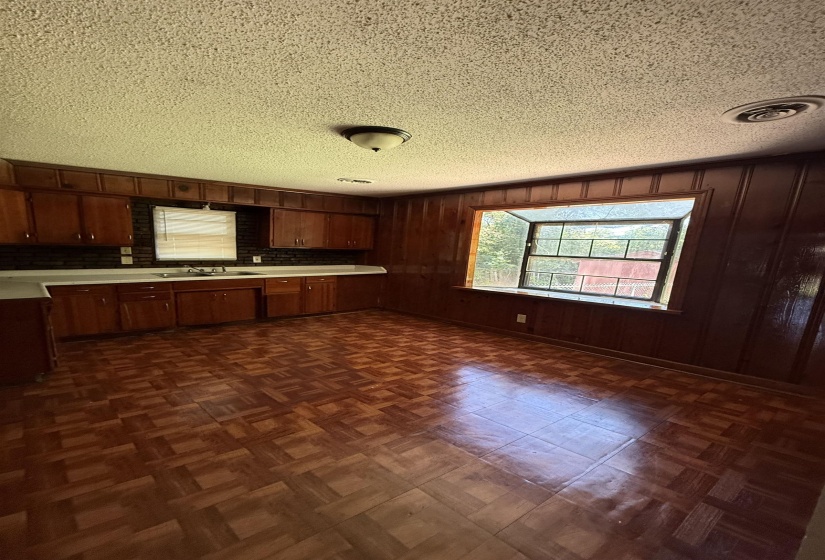 Kitchen featuring a sink, light countertops, a textured ceiling, backsplash, and brown cabinetry