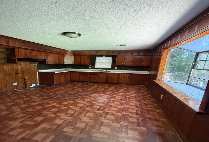 Kitchen featuring light countertops, a textured ceiling, a sink, wooden walls, and a peninsula