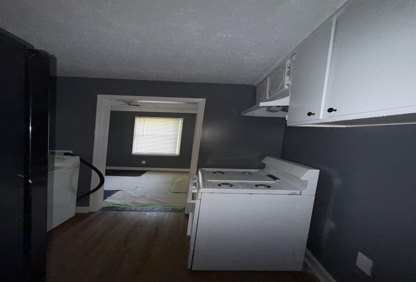 Kitchen featuring white stove, dark wood-style flooring, white cabinetry, a textured ceiling, and baseboards