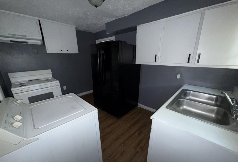 Kitchen with freestanding refrigerator, under cabinet range hood, white range with gas cooktop, washer / dryer, and dark wood finished floors