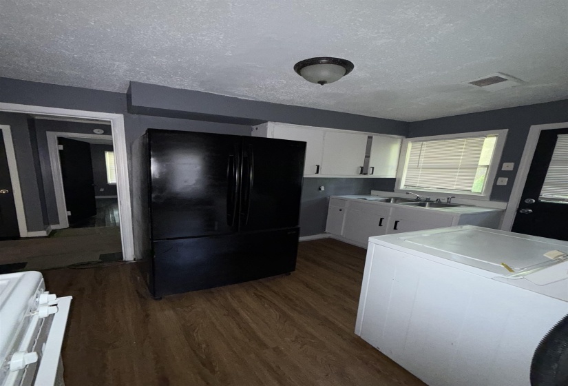 Kitchen featuring freestanding refrigerator, washer / clothes dryer, white stove, dark wood-type flooring, and a textured ceiling