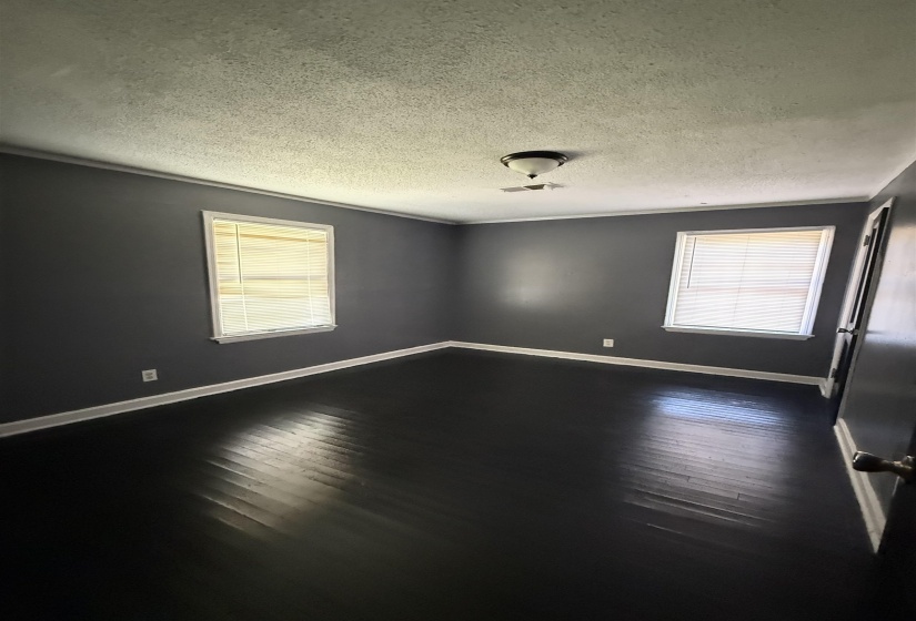 Empty room with baseboards, dark wood-type flooring, and a textured ceiling