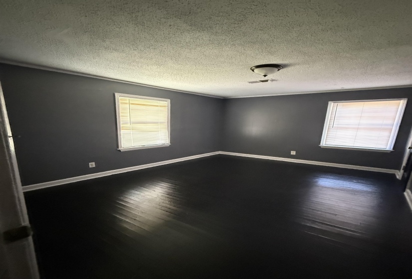 Unfurnished room featuring wood finished floors, baseboards, and a textured ceiling