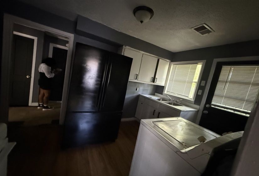 Kitchen featuring washer / clothes dryer, dark wood-style flooring, white cabinetry, a sink, and baseboards