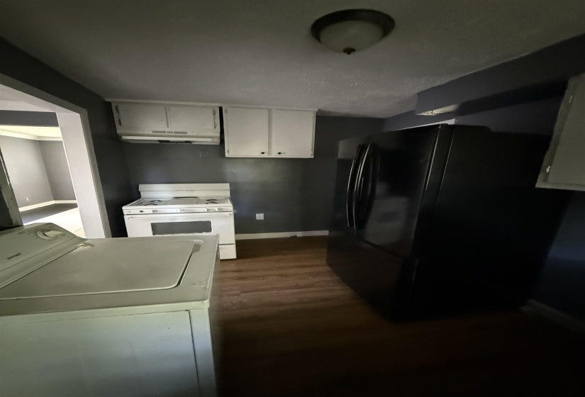 Kitchen featuring white range with gas cooktop, freestanding refrigerator, baseboards, white cabinetry, and dark wood finished floors