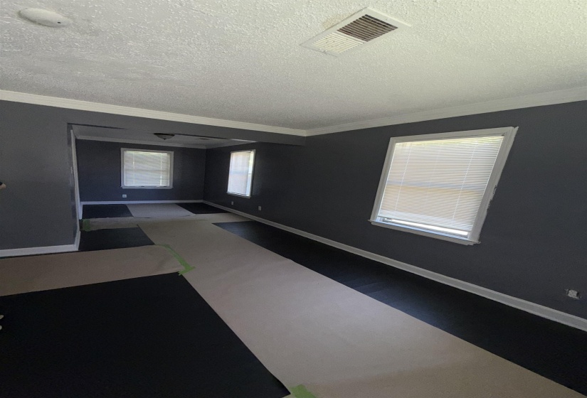 Empty room featuring a textured ceiling, crown molding, and baseboards