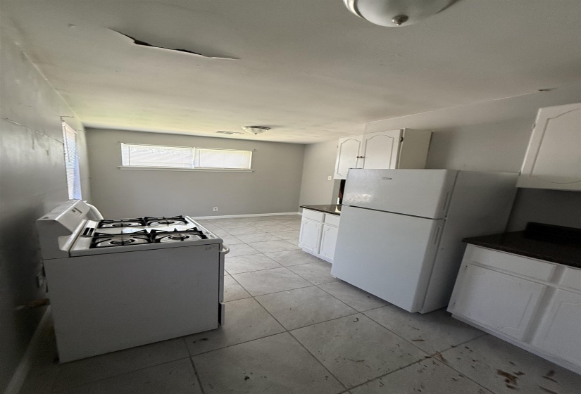 Kitchen with white appliances, dark countertops, white cabinetry, and light tile patterned floors