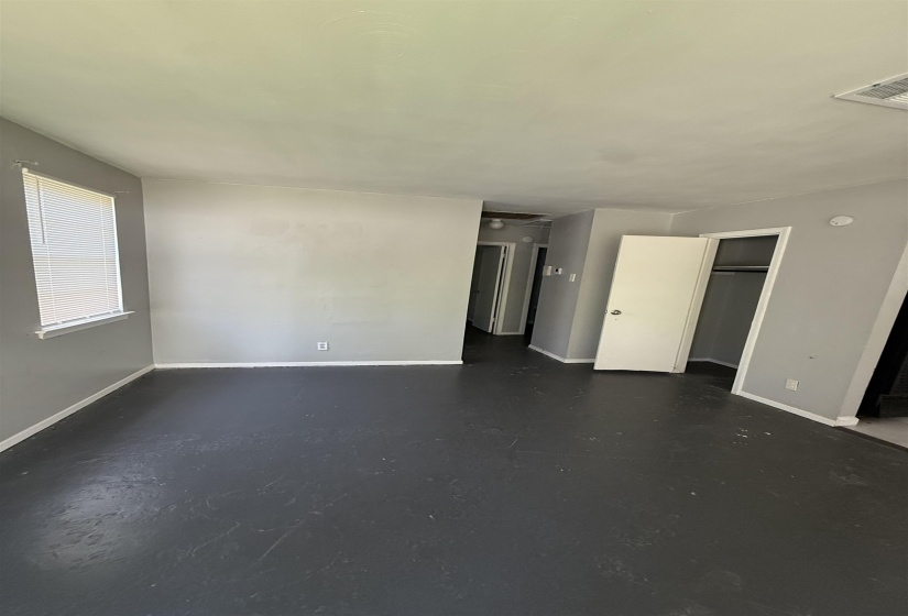 Unfurnished bedroom featuring finished concrete floors, baseboards, and a closet