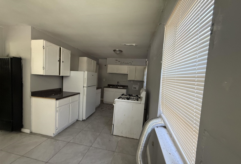 Kitchen featuring white appliances, a heating unit, a sink, white cabinetry, and light tile patterned flooring