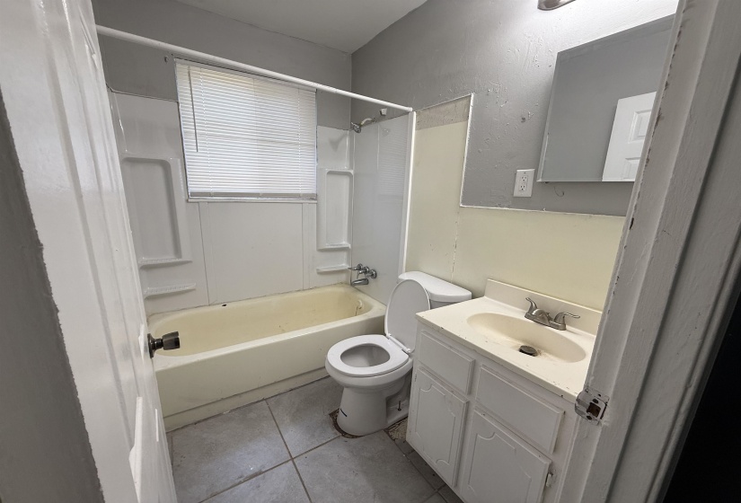 Full bath with bathing tub / shower combination, vanity, tile patterned floors, and toilet