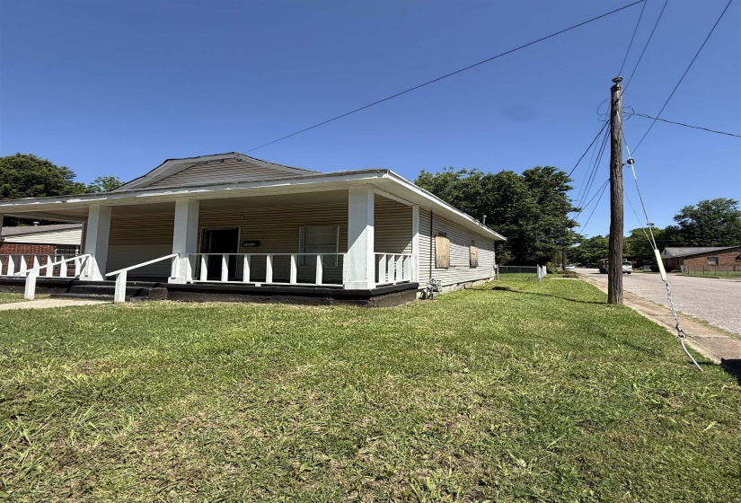 View of side of property featuring a porch and a yard