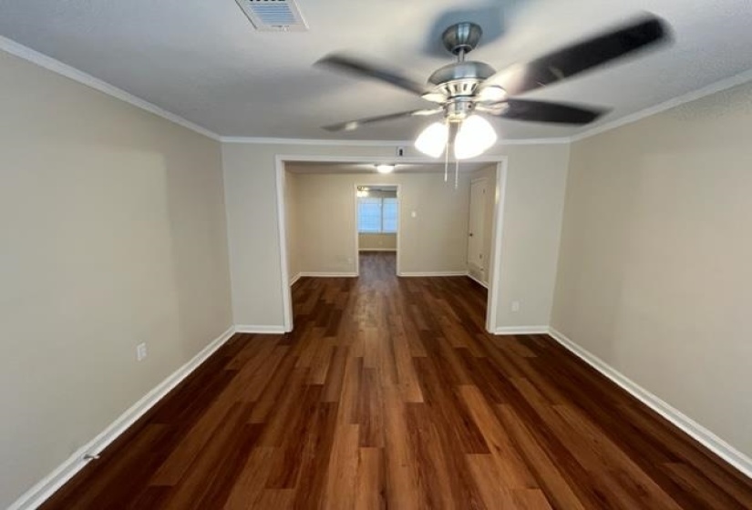 Spare room featuring wood finished floors, baseboards, ceiling fan, and crown molding