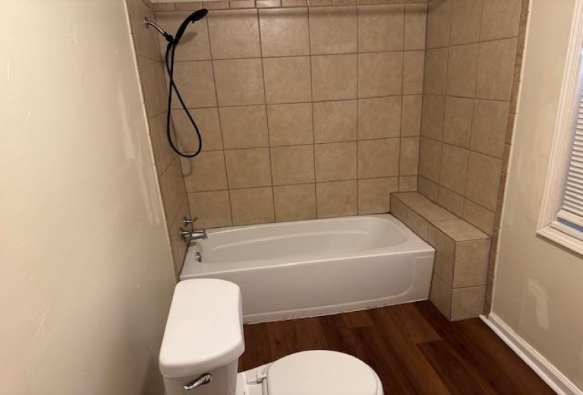 Bathroom featuring toilet, tiled shower / bath, and hardwood / wood-style floors