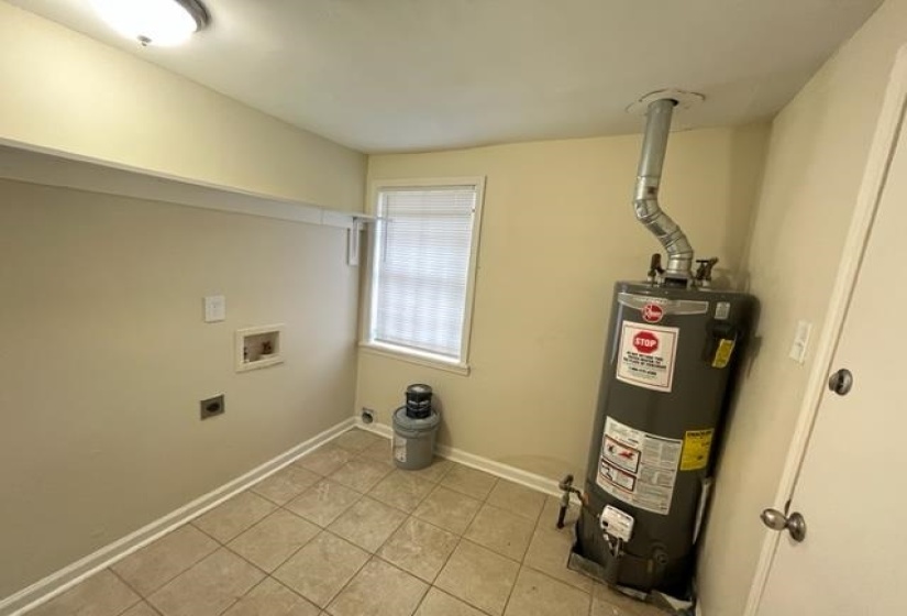 Laundry area featuring water heater, washer hookup, hookup for an electric dryer, light tile patterned floors, and baseboards