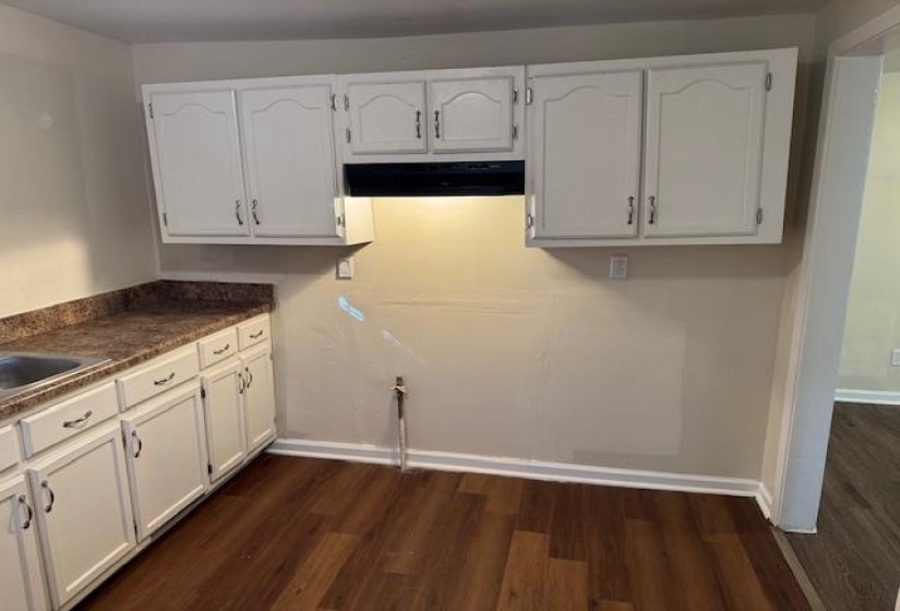 Kitchen with white cabinets, dark hardwood / wood-style floors, and extractor fan