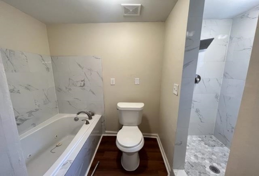 Full bath featuring a tile shower, toilet, a tub with jets, and wood finished floors