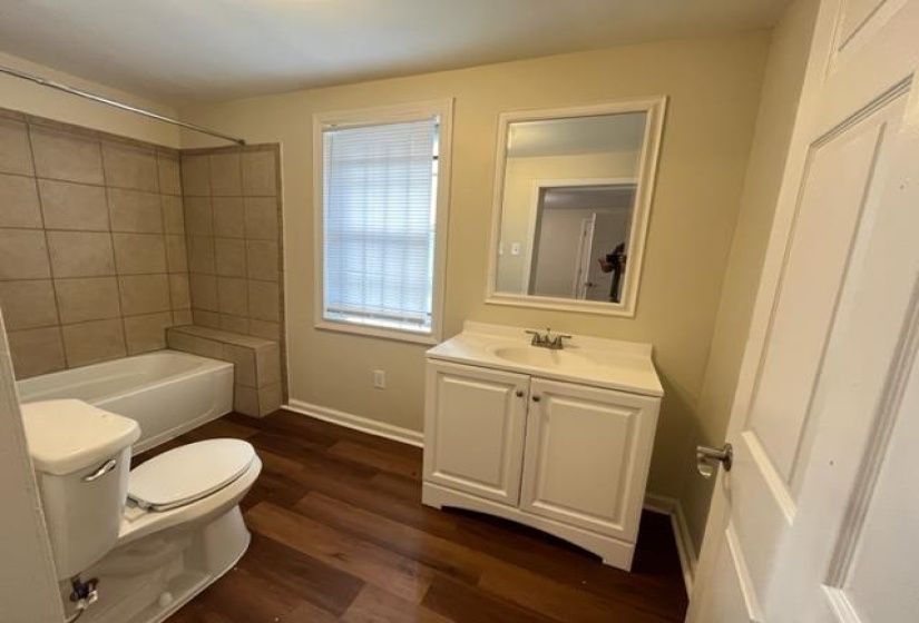 Bathroom featuring toilet, vanity, wood finished floors, bathing tub / shower combination, and baseboards