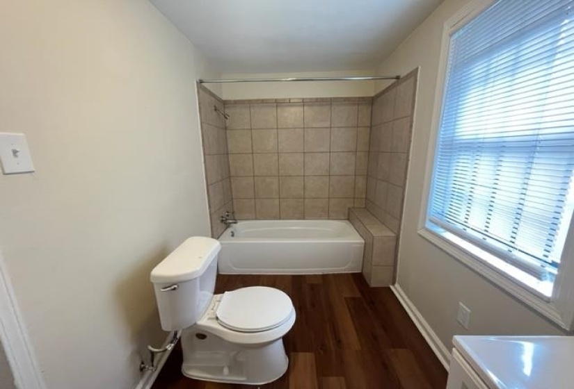 Full bath featuring toilet, wood finished floors, washtub / shower combination, baseboards, and vanity