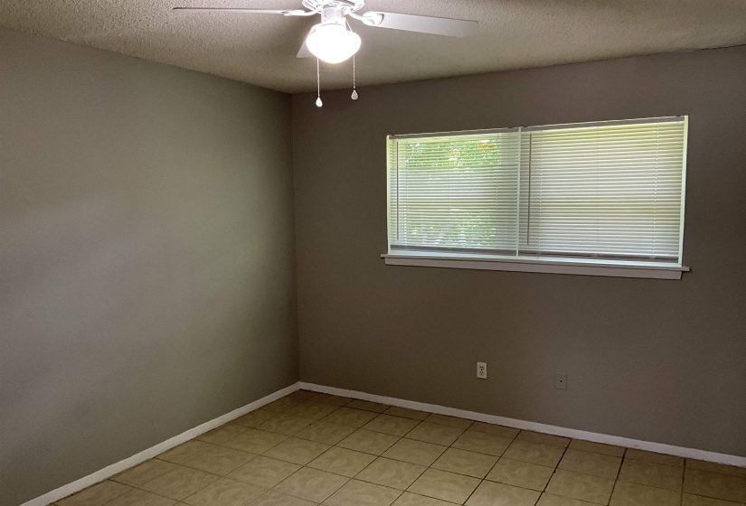 Spare room with a textured ceiling, ceiling fan, baseboards, and light tile patterned flooring