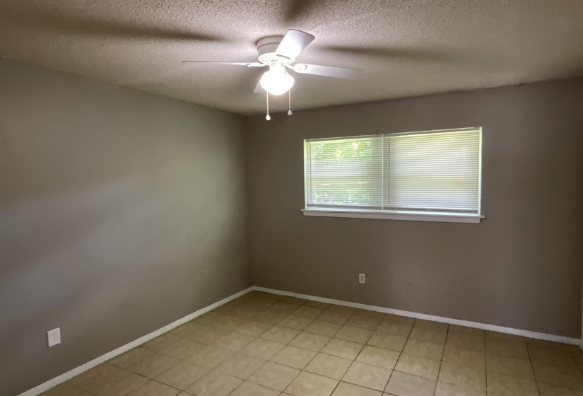 Unfurnished room with a textured ceiling, ceiling fan, and baseboards
