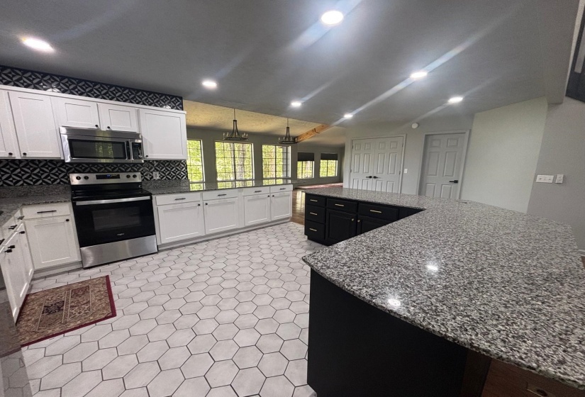 Kitchen featuring stainless steel appliances, white cabinetry, dark stone countertops, decorative backsplash, and a large island