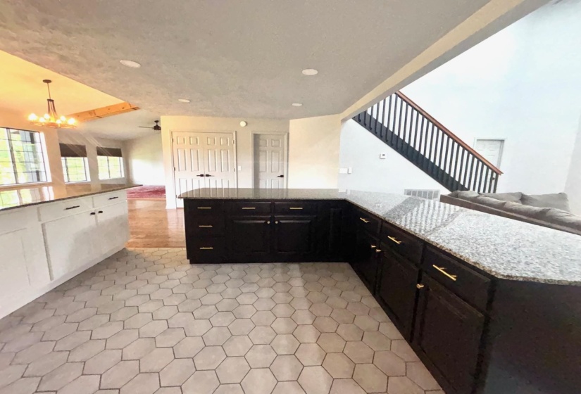 Kitchen with open floor plan, recessed lighting, light stone counters, and dark cabinets