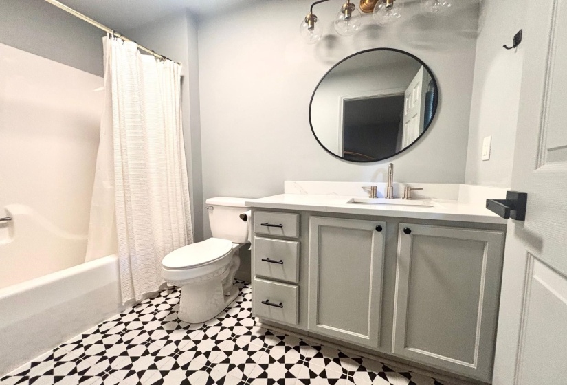 Full bath featuring tile patterned floors, vanity, toilet, and shower / bath combo with shower curtain