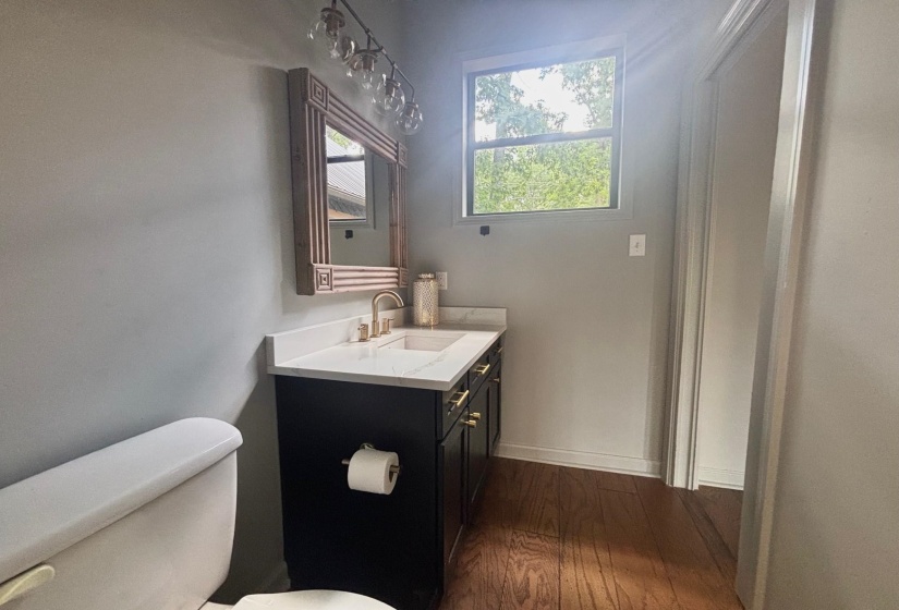 1/2 Guest Bath with toilet, wood finished floors, vanity, and baseboards