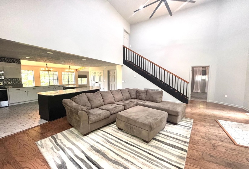 Living area with a chandelier, high vaulted ceiling, wood finished floors, stairs, and baseboards