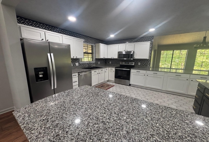Kitchen featuring appliances with stainless steel finishes, white cabinetry, a sink, dark stone countertops, and recessed lighting