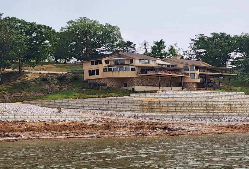 View of front of home with a deck with water view and driveway