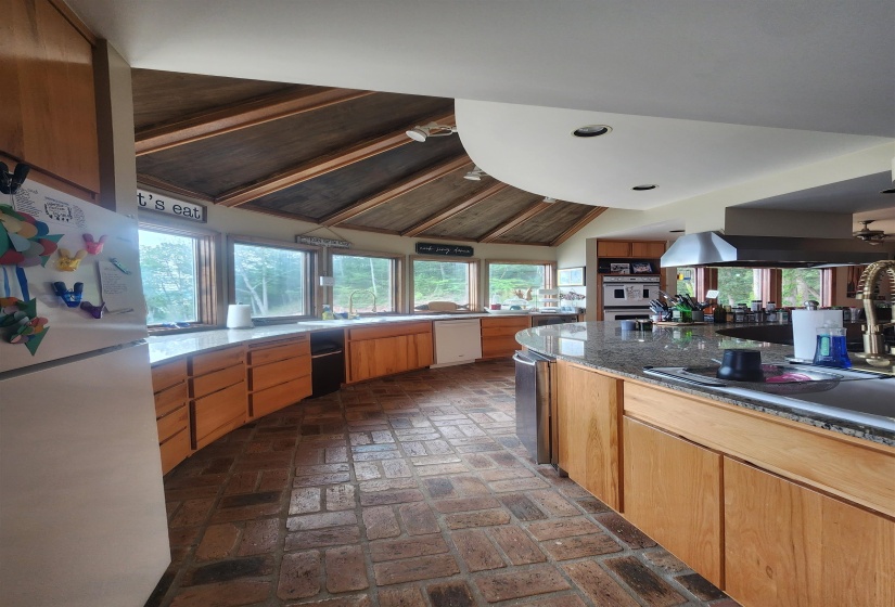 Kitchen with white appliances, brick flooring, vaulted ceiling, recessed lighting, and plenty of natural light