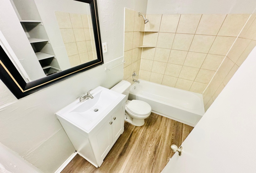 Full bathroom featuring vanity, tiled shower / bath combo, toilet, and hardwood / wood-style flooring